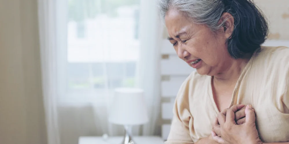 Người phụ nữ lớn tuổi ôm ngực vì khó thở, đau tức ngực tại nhà